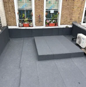 Flat rooftop with potted plants and windows.