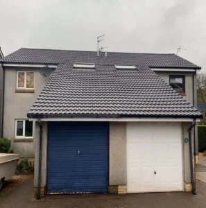 House with two garages and gray roof.